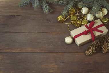 Paketlenmiş hediye bağlı kırmızı kurdele, çam kozalakları, altın top, Aralık