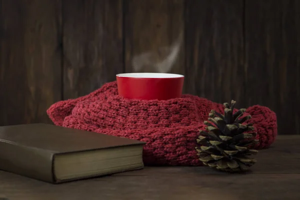 Piros pohár, sál, könyv, fenyő kúp, a fából készült háttér — Stock Fotó