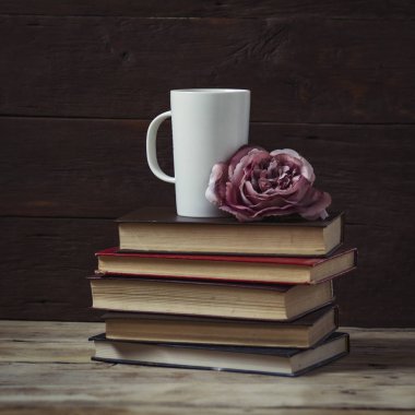 Gül bud, kitap ve beyaz bir fincan. Ahşap backgro kompozisyonu