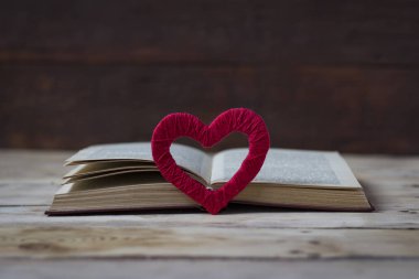 Kalp el, ahşap arka plan üzerinde açık bir kitap