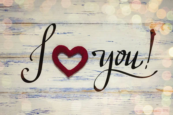 Heart handled on a white wooden background. The inscription I lo