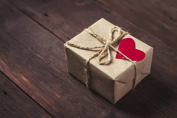 Small gift box with heart on wooden background — Stock Photo, Image