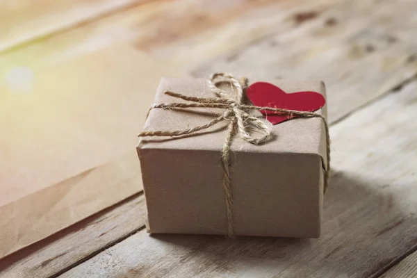 On a wooden table with envelope and a gift box with a heart. Add — Stock Photo, Image