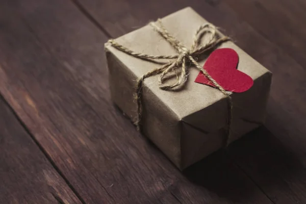 Подарочная коробка с красным сердцем на деревянном фоне — стоковое фото