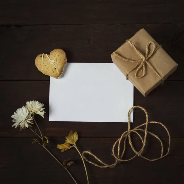 Folha de papel em branco, um biscoito na forma de um coração e um presente — Fotografia de Stock