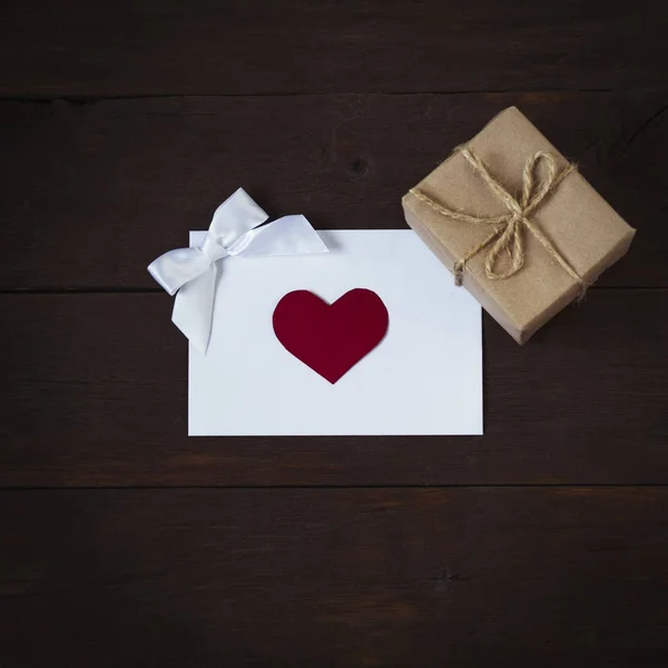 Composition avec enveloppe avec coeur, un arc et boîte cadeau sur un de — Photo