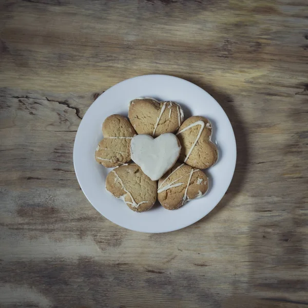 Placa com biscoitos na forma de corações em um fundo de madeira . — Fotografia de Stock