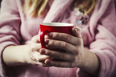 Bir kadın bir pembe elbise içinde kırmızı bir fincan çay tutar