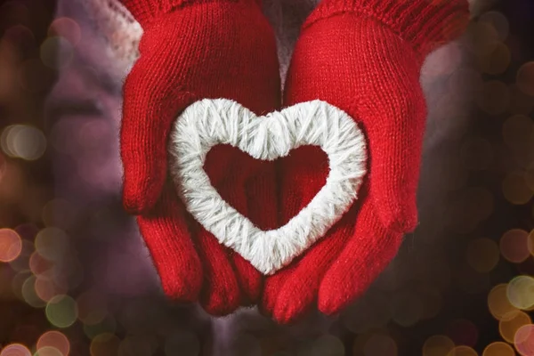 A girl in red gloves holds a heart. Flat lay. Bokeh