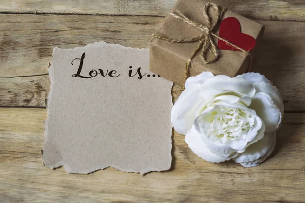 Inscripción en un papel El amor es... Caja de regalo con corazón — Foto de Stock