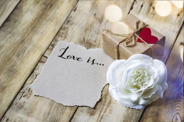 Concepto de San Valentín. Inscripción en un pedazo de papel El amor es — Foto de Stock
