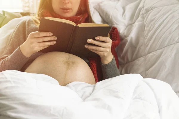 Chica embarazada en la cama leyendo un libro — Foto de Stock