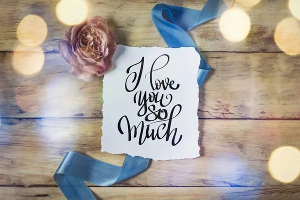 Inscription I love you so much. Rose and blue ribbon on a wooden — Stock Photo, Image