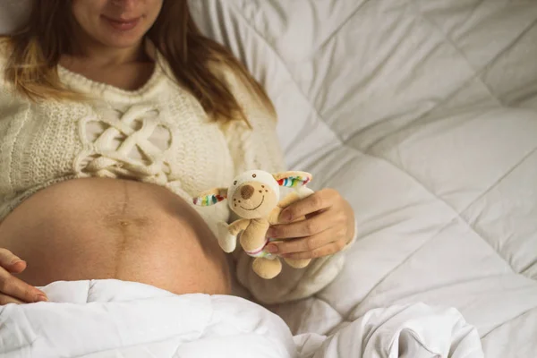 Jovem grávida segurando um brinquedo na mão — Fotografia de Stock