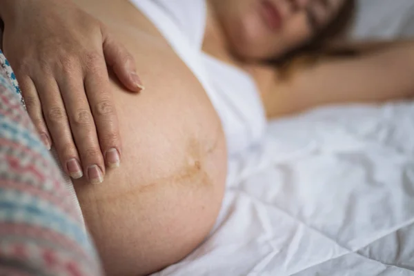 La mujer embarazada descansa en su cama. Concéntrate en la mano — Foto de Stock
