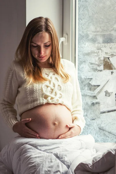 Młoda dziewczyna w ciąży trzyma ręce w brzuchu. Poza wi — Zdjęcie stockowe