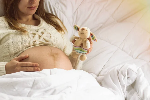 Pregnant young girl in her room holds a toy in her hand, another — Stock Photo, Image