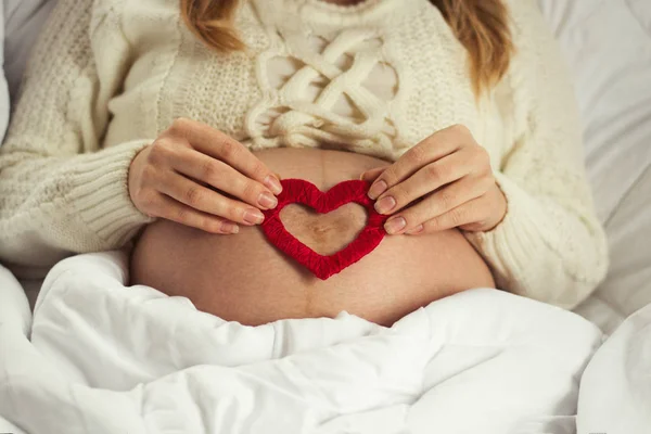 Jovem grávida em seu estômago segura o coração vermelho do ha — Fotografia de Stock