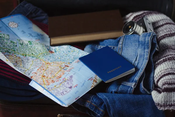 Travel concept. On the suitcase, clothes, passport, map, book an