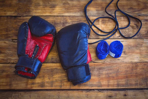 Boxing gloves, rope, taping bandages on a wooden table