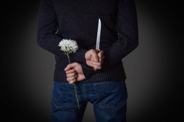 Adam bıçağı ve çiçek arkasından tutar. Kör da