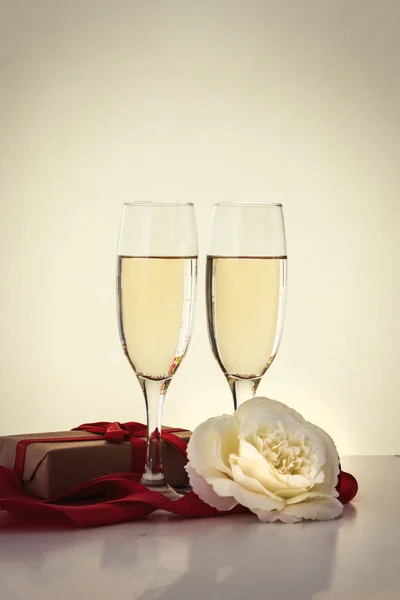Packaged gift, two glasses with champagne and a white rose flow