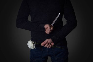 Adam bıçağı ve çiçek arkasından tutar. Kavramı 