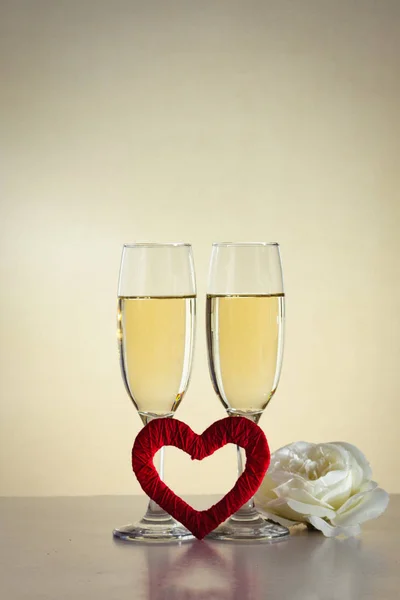 Dos copas con champán, un corazón rojo hecho a mano y un ros blanco — Foto de Stock