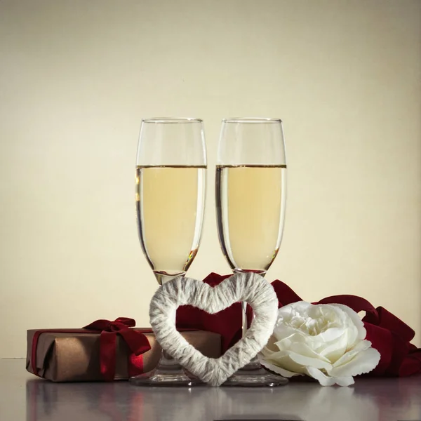 Two glasses with champagne, a red heart handmade, a gift wrapped — Stock Photo, Image