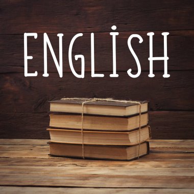 Ahşap arka plan üzerinde kitap yığını. Eklenen İngilizce metin