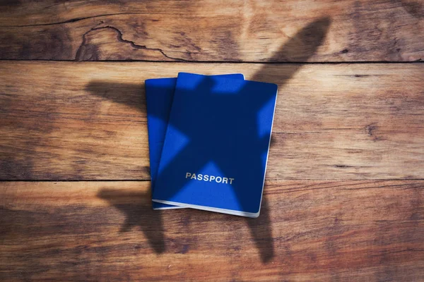 Reisekonzept. Blauer Pass und Flugzeug auf hölzernem Rücken — Stockfoto