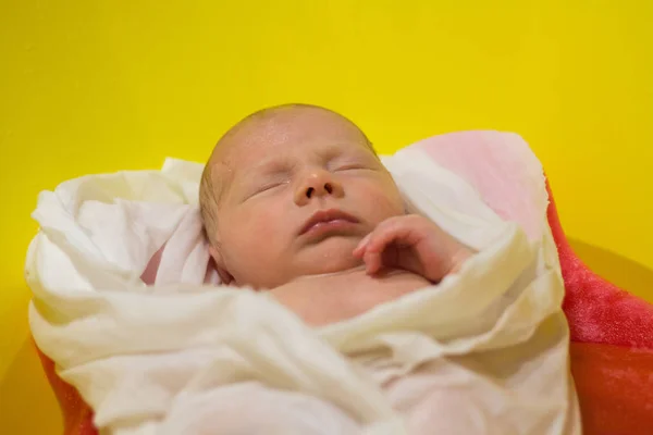 Bebé recién nacido Un paño blanco envuelto en una bañera amarilla —  Fotos de Stock