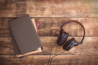 Kitaplar ve ahşap masa kulaklıktan resmi