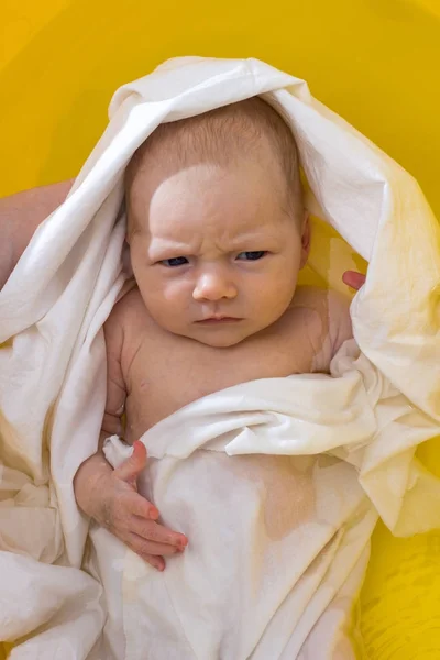 Ein Neugeborenes wird in einer gelben Badewanne gebadet. Ansicht von oben — Stockfoto