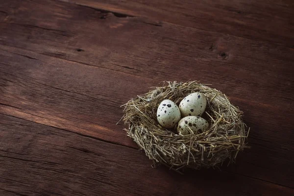 Quail eggs in a nest on a wooden background. Taken at an angle — Stock Photo, Image