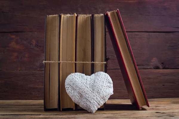 Livros e um coração branco em um fundo de madeira — Fotografia de Stock