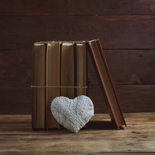 Books and a White Heart on a Wooden Background