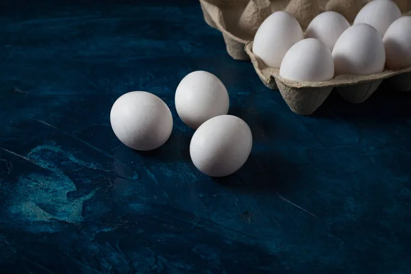 Fehér tojás egy nyitott kartondobozban a kék háttér és a f — Stock Fotó
