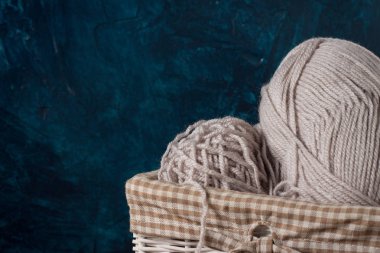 Açık gri örgü, mavi bir arka plan üzerinde bir sepet içinde iplik