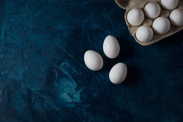 Fehér tojás egy nyitott kartondobozban a kék háttér és a f — Stock Fotó