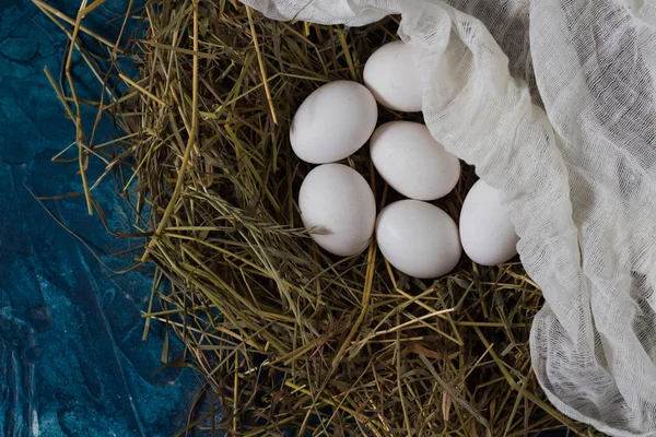 巣と青色の背景に白い生地に鶏の卵. — ストック写真