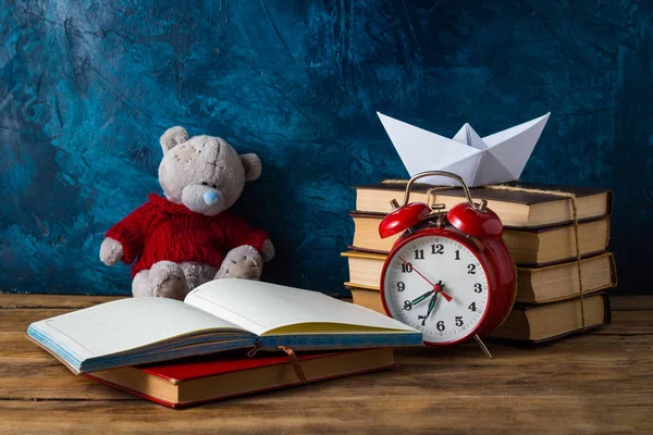Open Diary, Paper Boat, Books, Toy Bear, Red Alarm Clock on a da