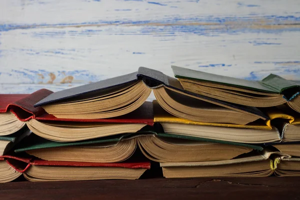 Libros abiertos apilados uno sobre el otro en el fondo de madera blanca —  Fotos de Stock
