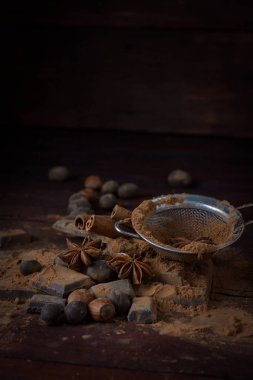 Çikolata, baharat, kakao, kaşıkla Metal süzgeç, fındık üzerinde