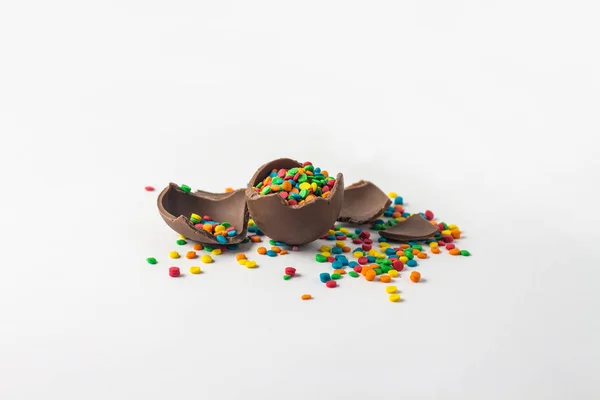 Zlomený čokoládový velikonoční vajíčko s pestrobarevným candy dekorace — Stock fotografie
