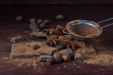 Çikolata, baharat, kakao, kaşıkla Metal süzgeç, fındık üzerinde Dar