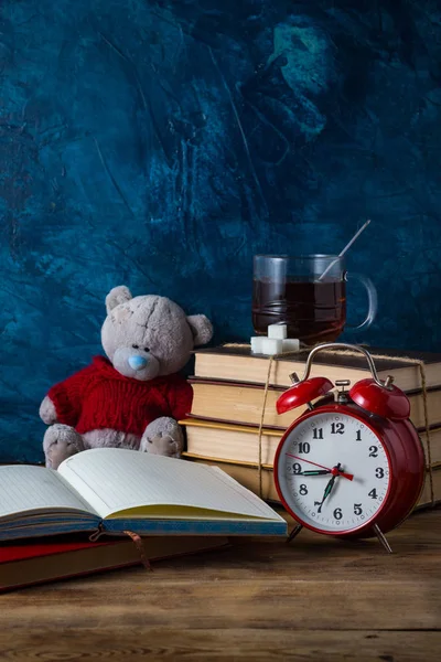Diário aberto, xícara de chá quente, livros, relógio de alarme vermelho em um blu escuro — Fotografia de Stock