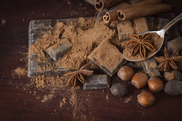 Ciocolată, condimente, lingură cu cacao, alune pe spatele din lemn — Fotografie, imagine de stoc