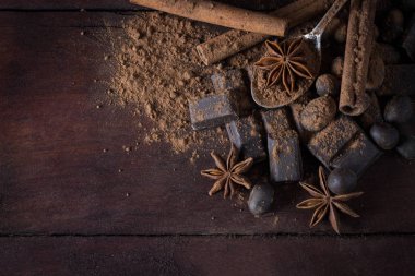 Siyah çikolata, baharat, çay kaşığı, kakao, tarçın üzerinde ahşap Ba