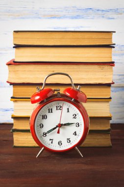 Kırmızı Alarm saati ve bir yığın kitap ahşap arka plan üzerinde